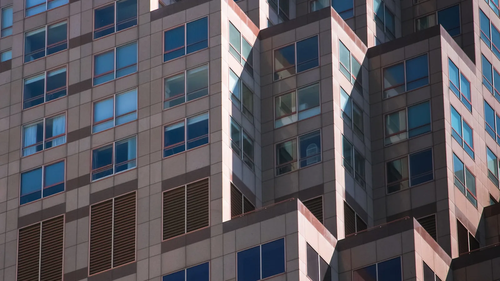 Modern commercial office tower facade with rows of glass windows