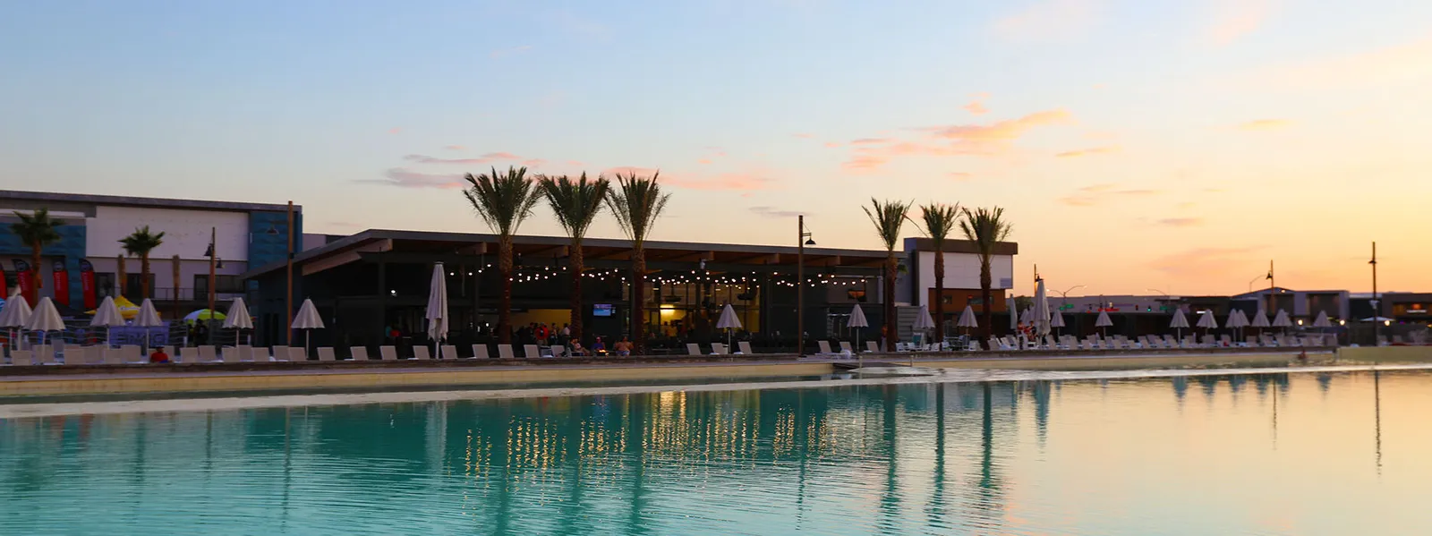 Revel Surf Park wave pool at sunset with palm trees and cabana lighting reflecting on the water