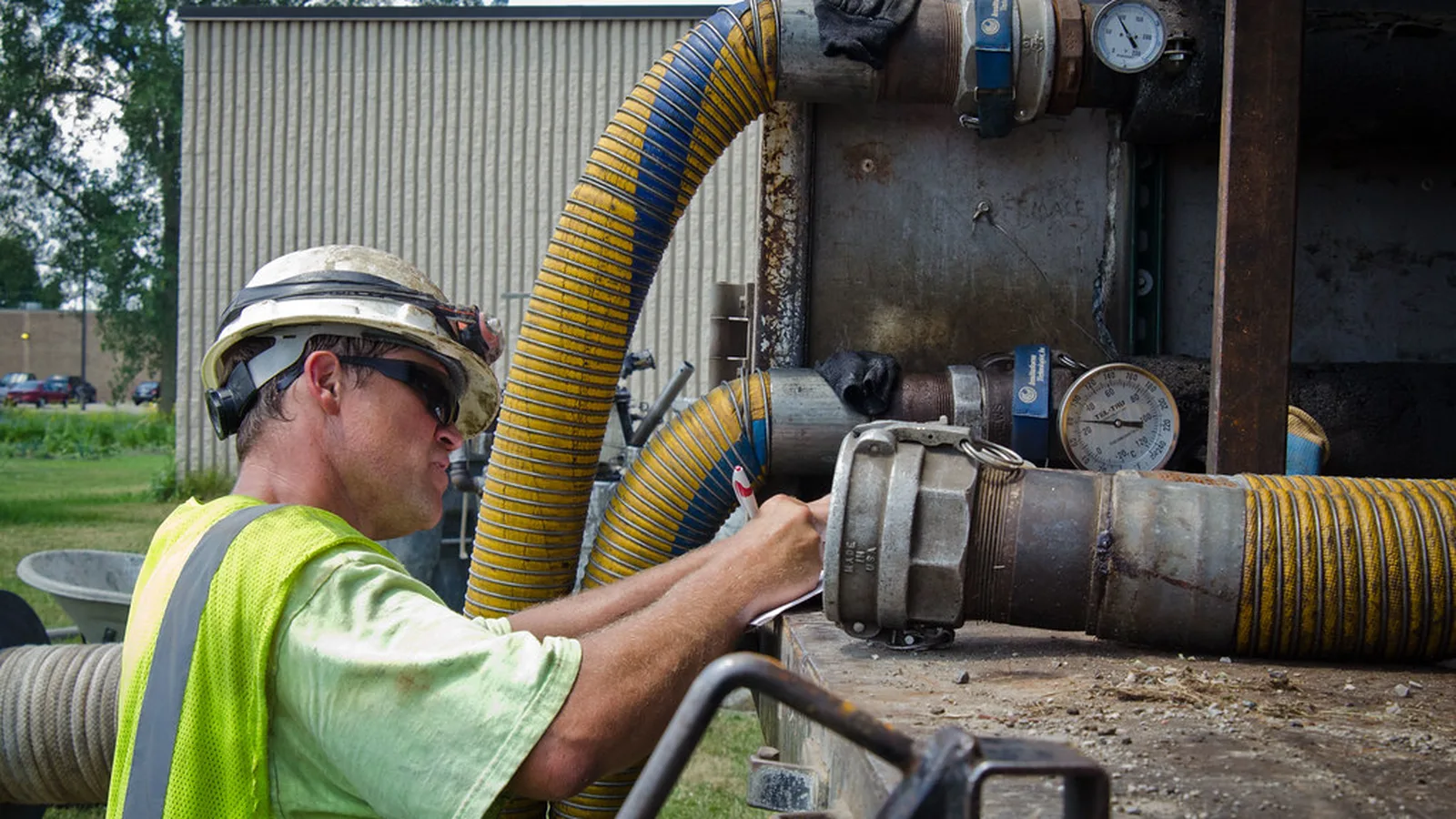Technician connecting hoses and pressure gauges on industrial process water piping
